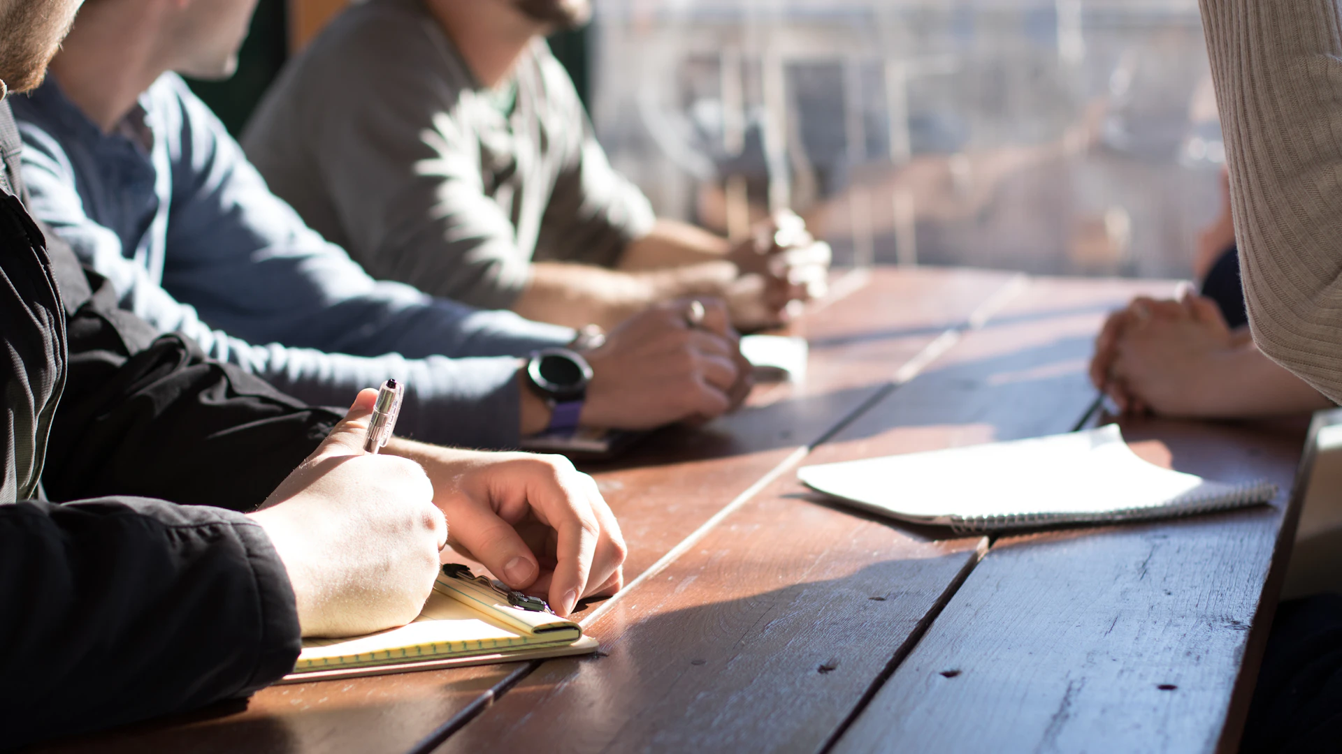 Colleagues taking notes together at a wooden table